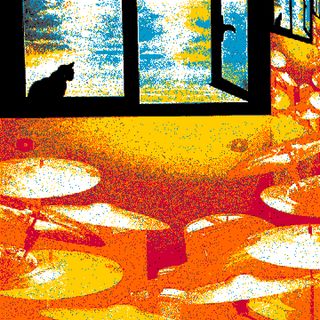 Una bateria sota una finestra on un gat reposa i mira a l'exterior.